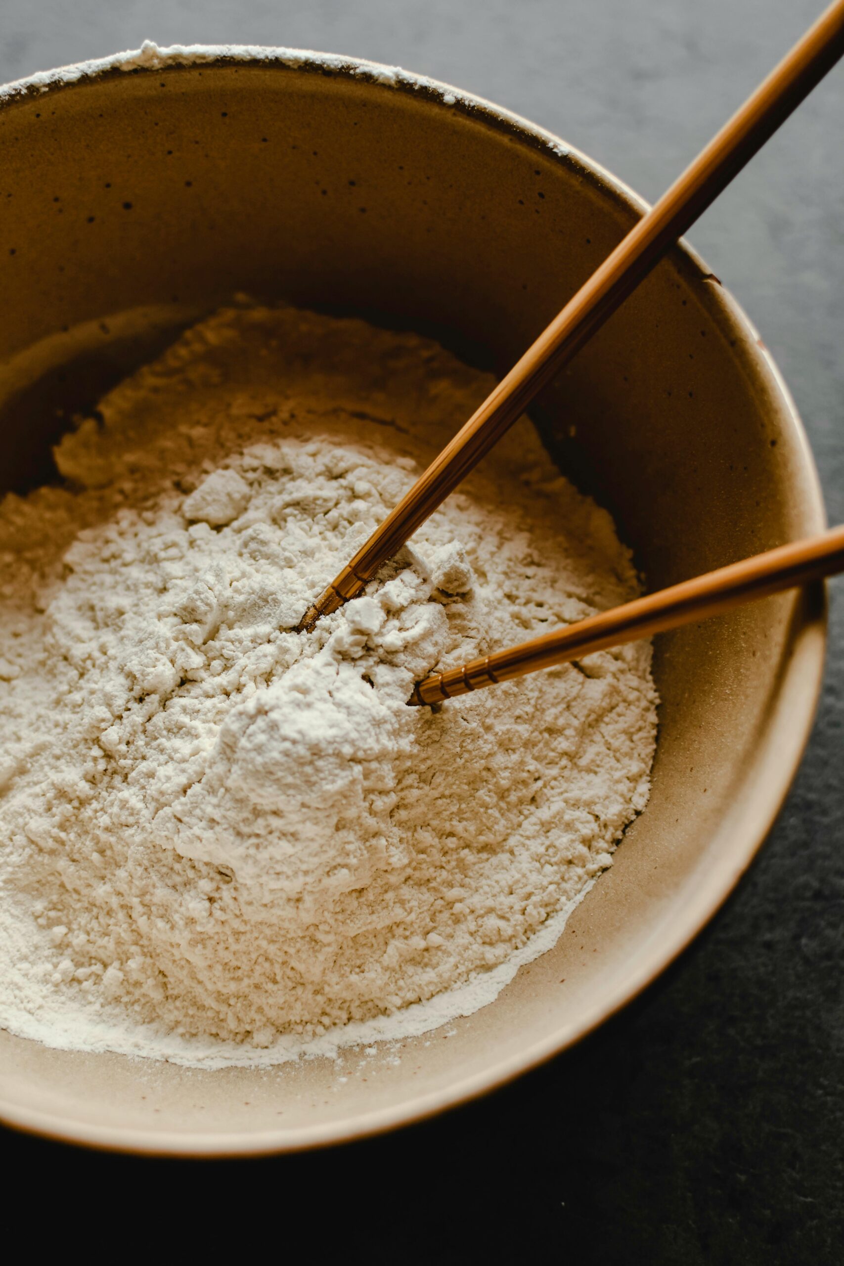 A detailed close-up of flour in a bowl with chopsticks. Ideal for culinary themes.
